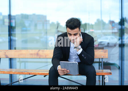 Man in suit arabic puts on sunglasses with tablet near business center Stock Photo