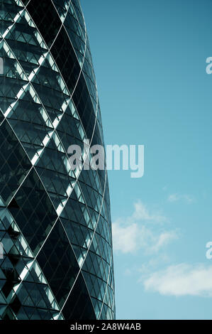 LONDON - JUNE 23, 2011: The 30 St Mary Axe building, also known as the Gherkin for its distinctive shape, stands in blue sky. Stock Photo