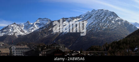 Saas Fee, Switzerland - march 2019: Traditional wooden Hotels and Huts in Saas-Fee Ski Resort with morning light on mountain range. Stock Photo