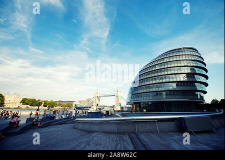 LONDON - OCTOBER 1, 2011: People walk along the Thames path in front of City Hall, the 10-story building designed by architect Sir Norman Foster.