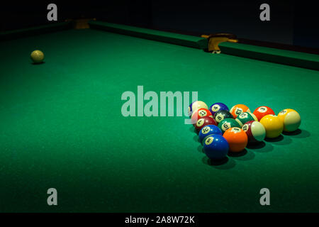 Set of used colorful numbered balls on old green billiards table. Horizontal background with equipment for Americal billiard cue sport game, leisure a Stock Photo