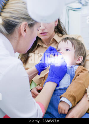 Childrens dentistry. Dental examination. Dentist treats the boys teeth. Female dentist treats teeth. Boy 0-1 age. Oral health. Stock Photo