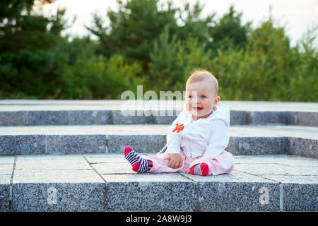 A small child sits on the ground and laughs. Stock Photo