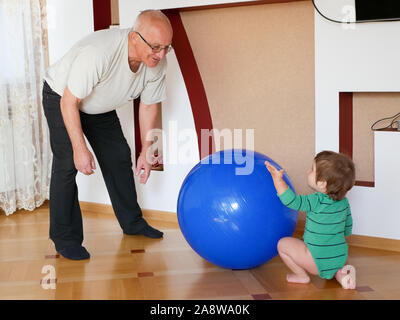 Grandfather plays with his grandson at home. Grandfather and grandson play with toys at home. Family relationships between grandfather and grandson Stock Photo