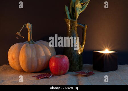 Halloween decoration with pumpkin apple, leaves and candle against the dark background Stock Photo
