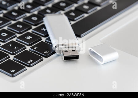 A silver USB flash drive with a laptop computer. Stock Photo