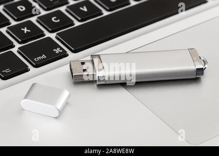 A silver USB flash drive with a laptop computer. Stock Photo