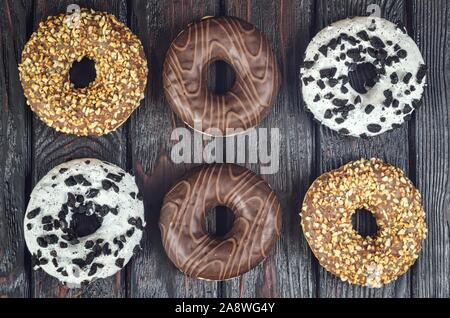 Background made of sweet dessert. Donuts with a hole and topping on a dark wooden table. Stock Photo