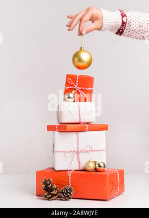 Woman decorating New Year tree of present boxes on white Stock Photo