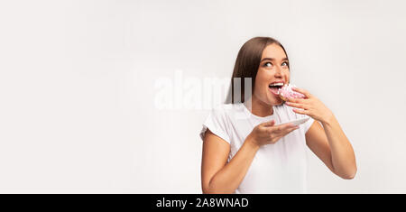 Pregnant Woman Eating Donut Standing On White Background, Panorama Stock Photo