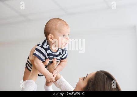 Loving mother lifting adorable newborn baby in air Stock Photo
