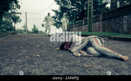 People in bacteriological protective suits running to help a woman Stock Photo