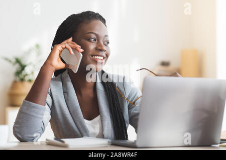 Young Black Businesswoman Talking On Cellphone While Working In Office Stock Photo