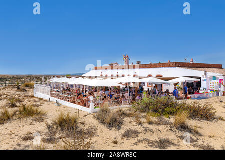 People having lunch at the outdoor beach restaurant at Barril beach. Santa Luzia Algarve, Portugal. Stock Photo