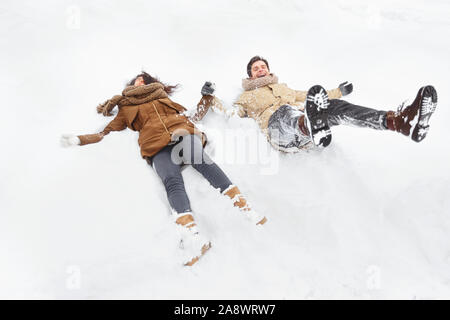 Couple Lying In Snow And Laughing Having Fun Outdoor Stock Photo