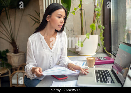 Busy businesswoman using laptop while filling tax declaration Stock Photo