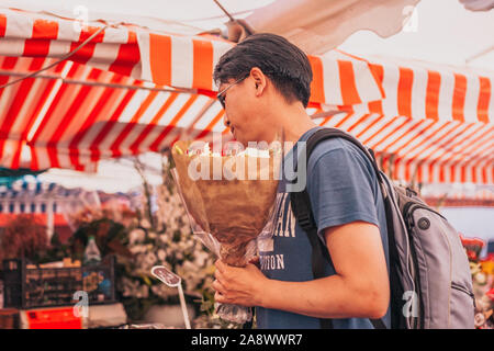 Nice, Provence / France - September 28, 2018: Asian man buying a bunch of flowers Stock Photo