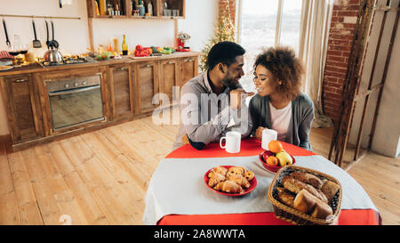 African-american couple enjoying tasty cookies in kitchen Stock Photo