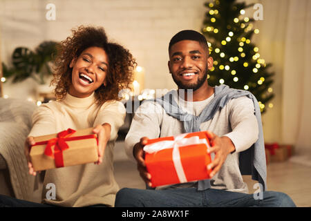 Merry Christmas! Joyful afro couple stretching xmas gifts Stock Photo