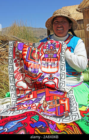 Woman displaying embroidered textiles on the Uros Floating Islands, Lake Titicaca, Peru Stock Photo