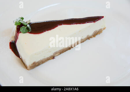 A slice of cheesecake with strawberry syrup, served in a white plate Stock Photo