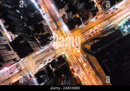 Car, taxi, and bus traffic on road intersection at night in Hong Kong downtown district, drone aerial top view. Street commuter Asia city life concept Stock Photo