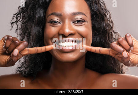 Happy black woman pointing at her perfect white teeth Stock Photo