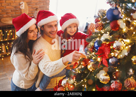 Happy family decorating Christmas tree with bubbles in living room Stock Photo