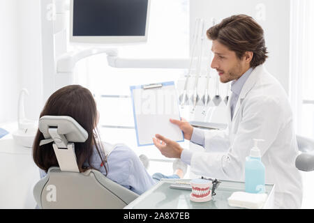 Dentist showing patient blank empty paper to fill up survey Stock Photo