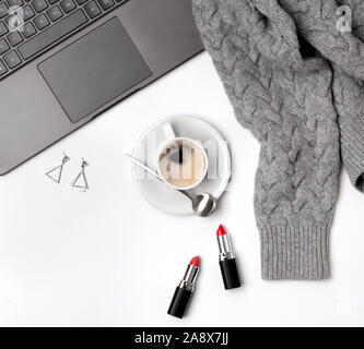 Laptop, coffee cup, sweater, lipsticks and glasses. Stylish office desk. Stock Photo
