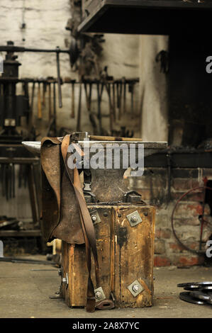 Anvil, hammer and leather apron in smithy Stock Photo