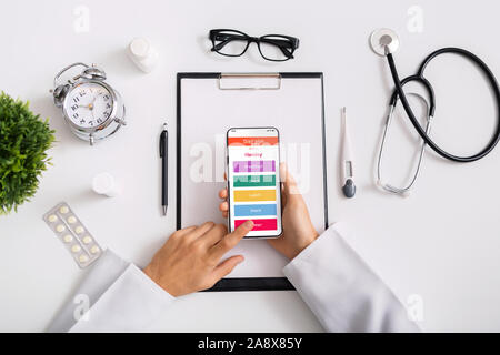 Doctor nutritionist using smartphone with opened daily diet plan application Stock Photo