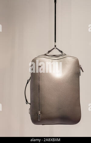 Womens silver color leather backpack hanging in shop. Gray Satchel bag in store window Stock Photo