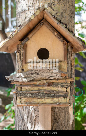 brown wooden birdhouse hanging from tree. Blured background Stock Photo