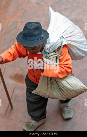 Old man carrying sacks of food from the marketplace in Cuenca Ecuador Stock Photo