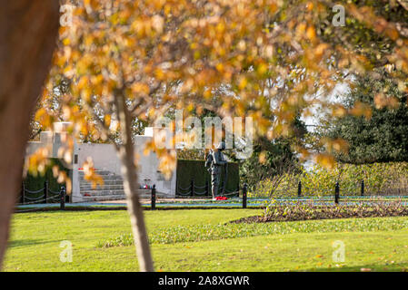 Bronze statue of a British ‘Tommy’ soldier in front of the Lutyens designed war memorial in preparation for Remembrance Sunday. Autumn leaves Stock Photo