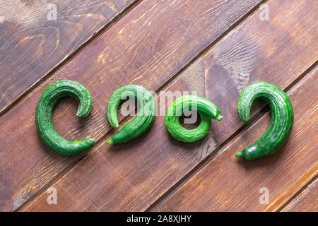 Ugly organic garden cucumbers on wooden background Stock Photo