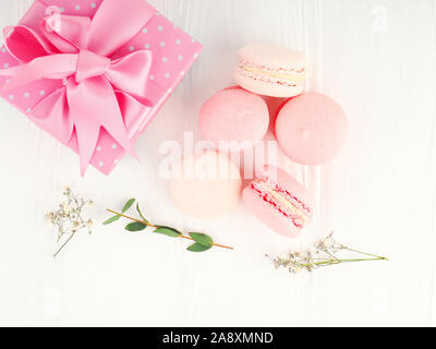 Gift box and macarons on whie table background with copy space to write. several white and pink sweet tender macaroons on a white background. Stock Photo