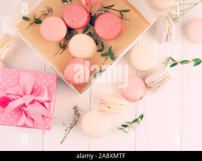 Gift box and macarons on whie table background with copy space to write. several white and pink sweet tender macaroons on a white background. Stock Photo