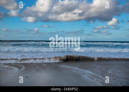 Cloudscape and seascape with waves washing onto sandy beach Stock Photo