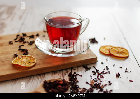 Cup of hibiscus tea (karkade, red sorrel, Agua de flor de Jamaica) on a table. Drink made from magenta calyces (sepals) of roselle flowers. Stock Photo