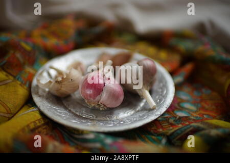 Garlic bulbs on a silver plate and vintage cloth. Stock Photo