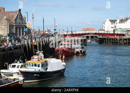 The Red Road and Pedestrian Swing Bridge with Fishing Boats on the River Esk and Holidaymakers in Whitby North Yorkshire England United Kingdom UK Stock Photo