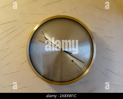 Round metal clock on white wall Stock Photo