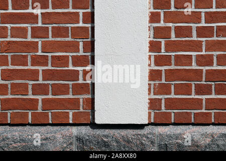 Brownish red brick wall and grey rock wall with white details. Surface of an exterior wall of a building. Beautiful clean architectural details. Stock Photo