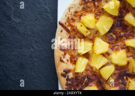 A cooked cheese and ham pizza, bought from a supermarket, that has had additional chunks of tinned pineapple added. England UK GB Stock Photo