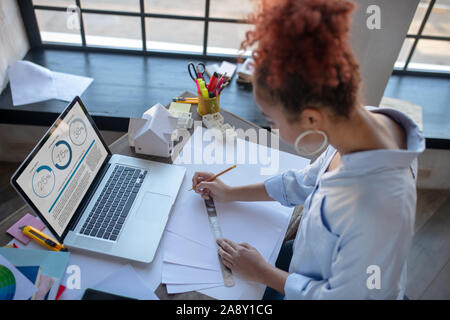 Top view of woman using ruler while making sketches Stock Photo