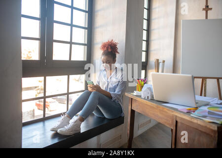 Designer enjoying break while using smartphone Stock Photo