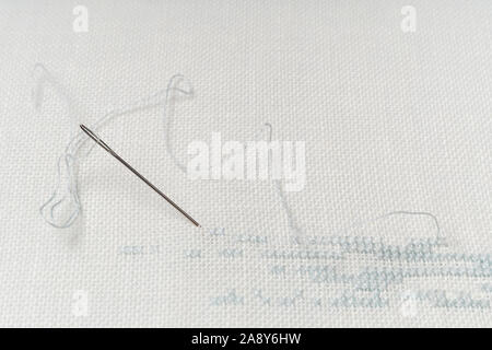 White canvas background with sewing tools and colorful threads. Embroidery concept. Mockup for hobby. Stock Photo