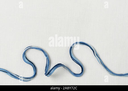 White canvas background with colorful threads. Embroidery concept. Mockup for hobby. Stock Photo